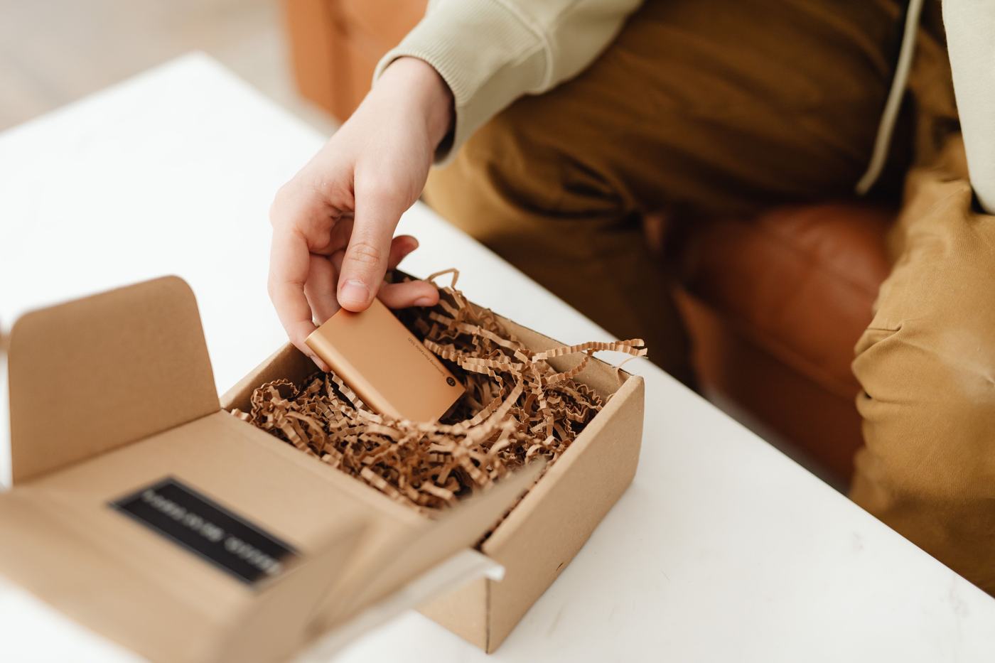 Hands open a small cardboard delivery box on a table
