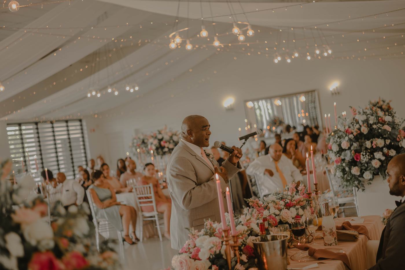 A man gives a speech into a microphone at a wedding reception
