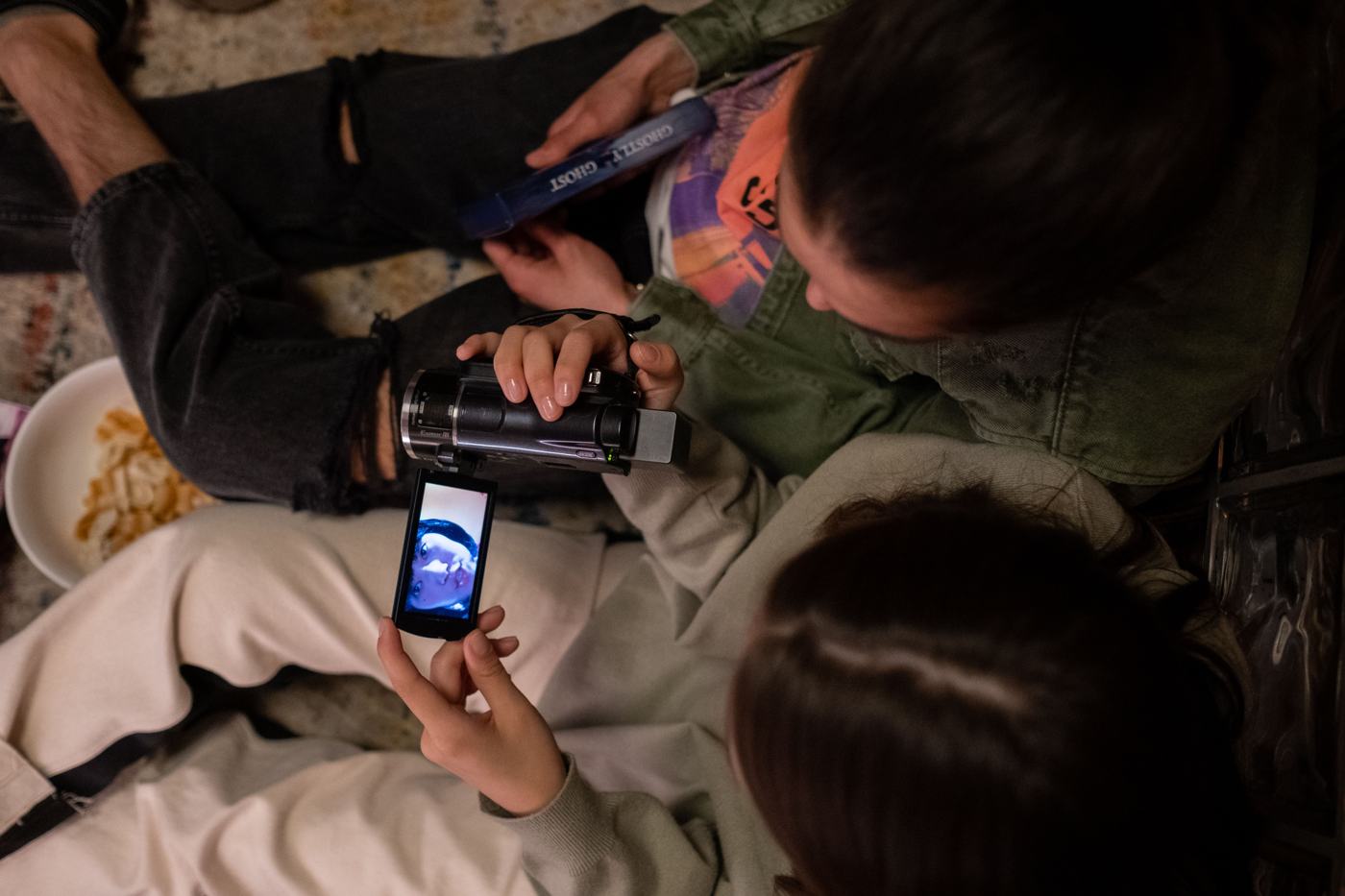 Two friends watch footage on the screen of a small camcorder